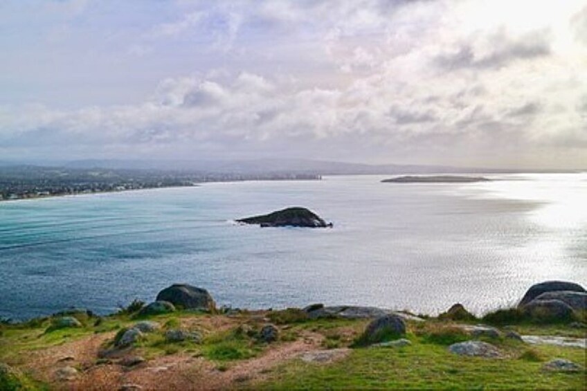 A coastal landscape with a large body of water, a small island, and rocky terrain in the foreground. 2