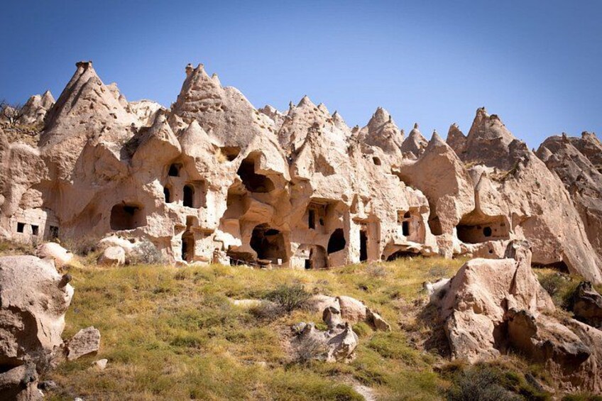 A landscape with rock formations resembling houses, a grassy area, and a clear sky. 2