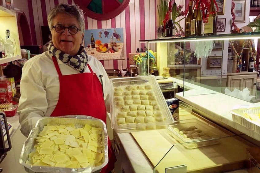 Una persona en una cocina sosteniendo bandejas de comida, con estantes y utensilios de cocina al fondo. 2