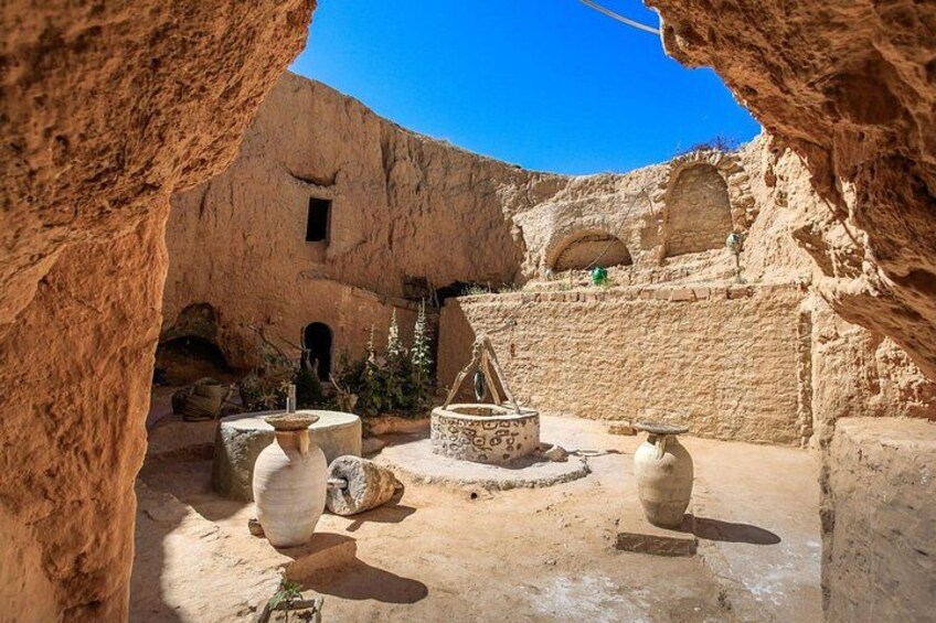 A traditional village with stone structures, pottery, and a central water feature. 5