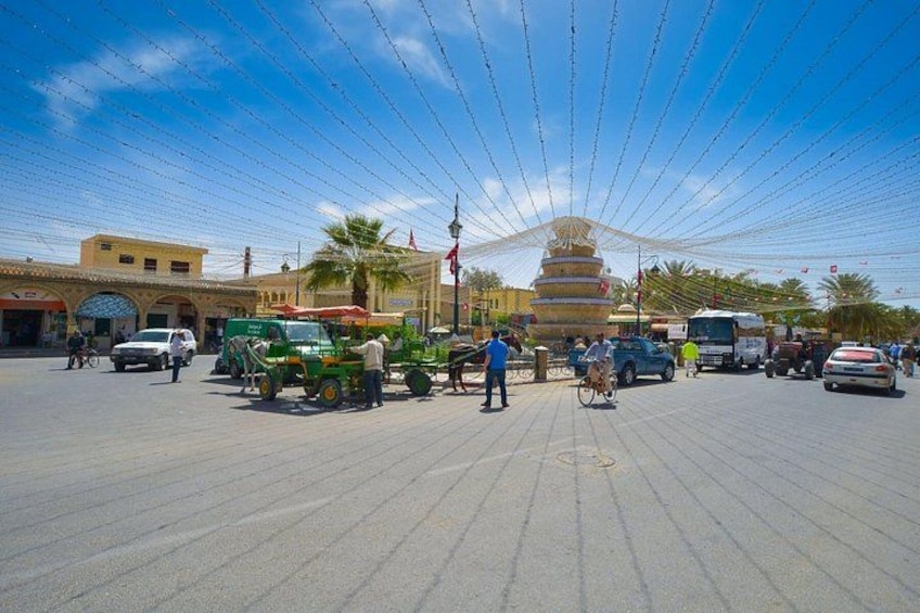 A plaza with a large, multi-tiered fountain, palm trees, and a clear blue sky. 4