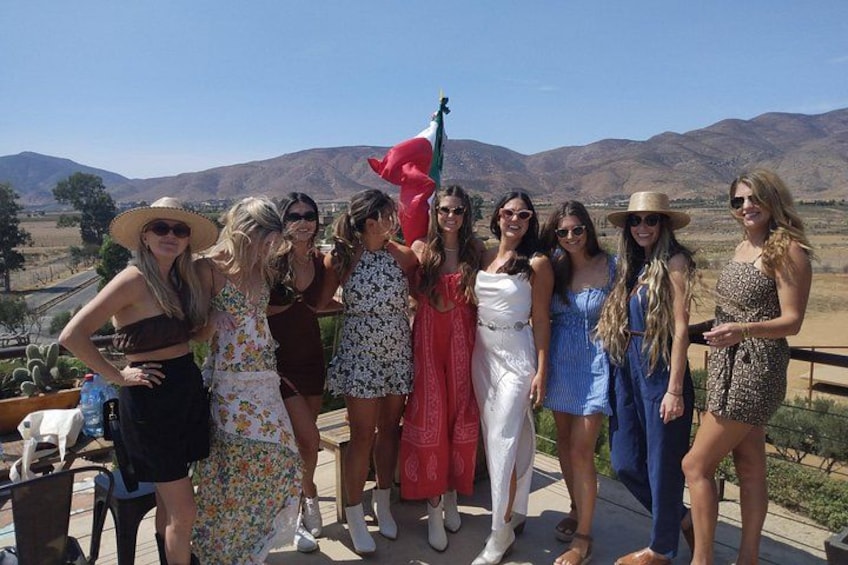 A group of people standing on a terrace with a mountainous landscape in the background. 3