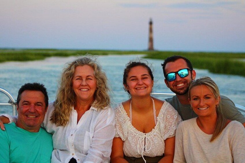 A group of people on a boat with a lighthouse in the background. 5