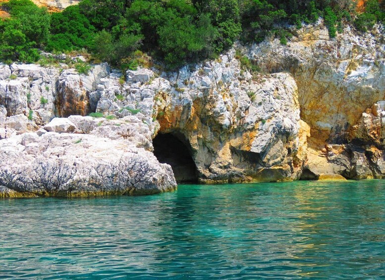 A rocky coastline with a cave entrance and clear turquoise waters. 3