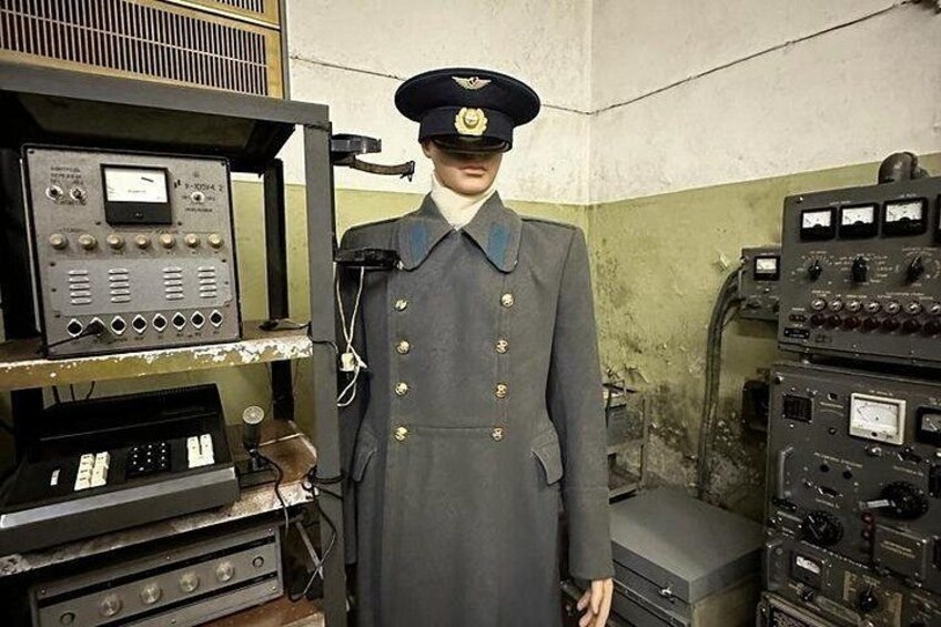 Une personne en uniforme, debout devant de vieux appareils électroniques. 3