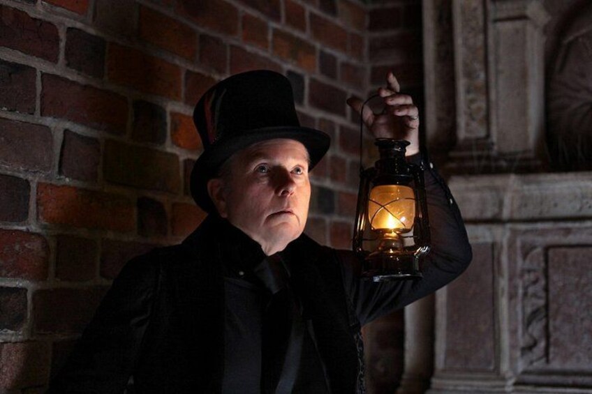 A person holding a lantern against a brick wall. 2