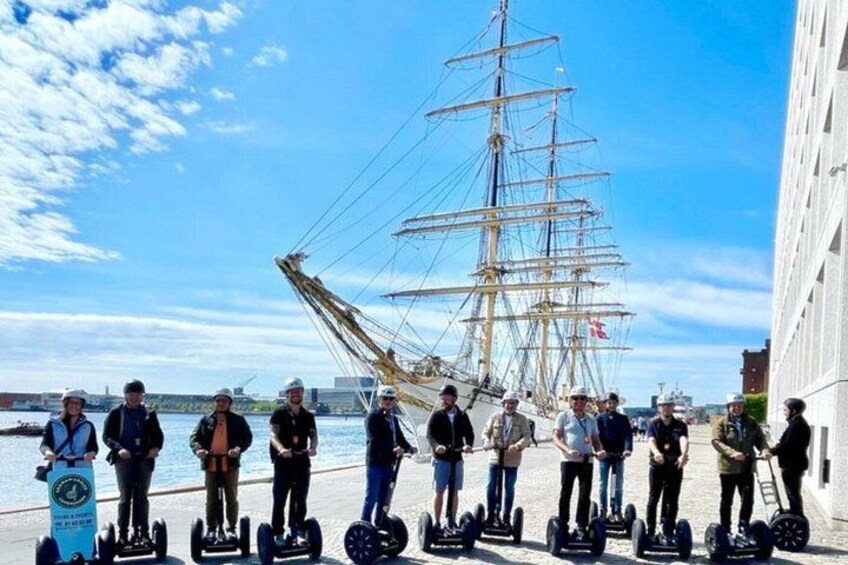 A group of people on segways near a tall ship. 2