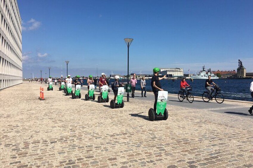 People riding Segways along a waterfront promenade. 1