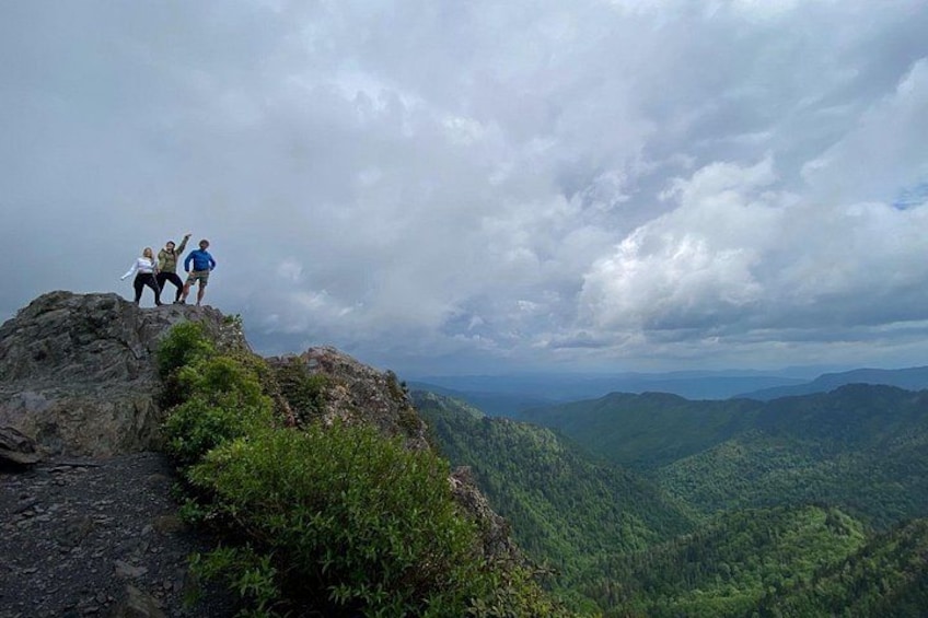 A group of people standing on a rocky outcrop overlooking a valley. 1