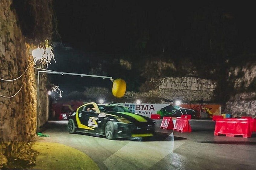 A car parked in a dimly lit area with a sign for BMA Paints in the background. 5