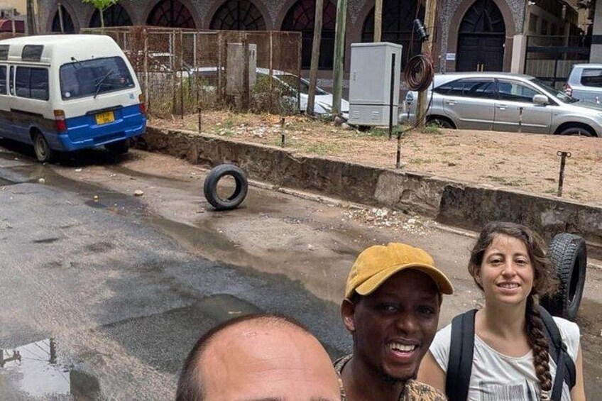A street scene with a white van, a tire on the ground, and a building with arched windows in the background. 3