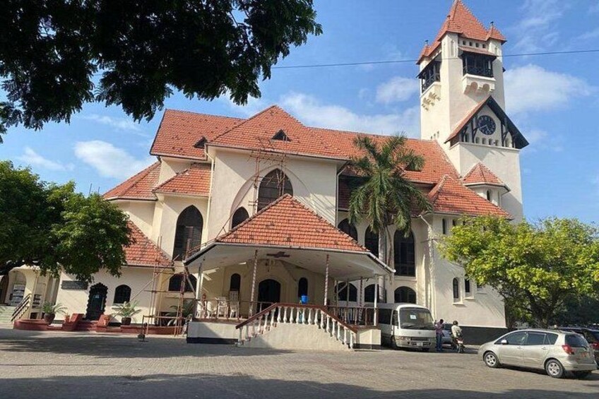 A church with a bell tower, a covered entrance, and a palm tree in the foreground. 1