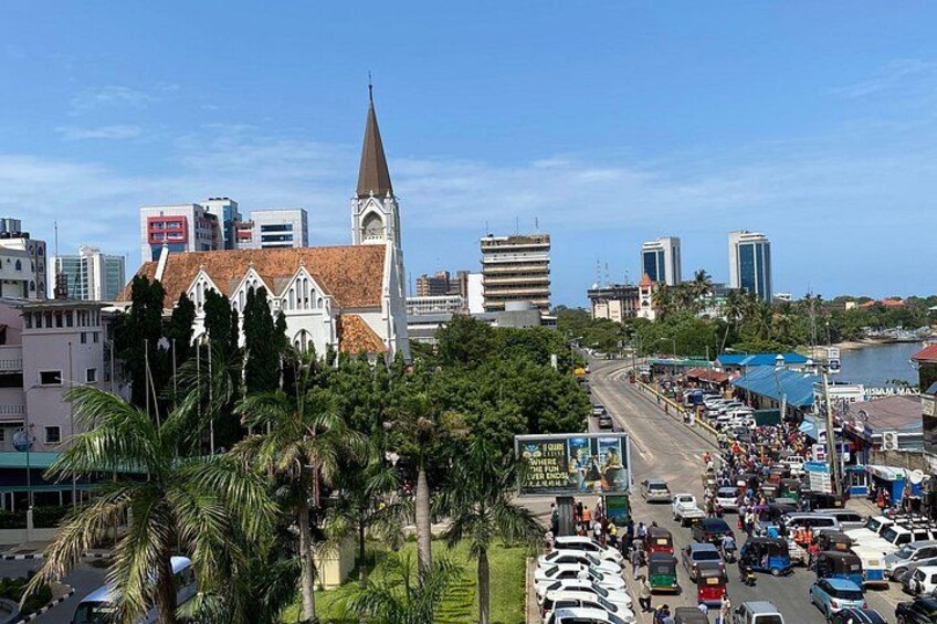 A busy urban street with a prominent church, palm trees, and modern buildings. 5