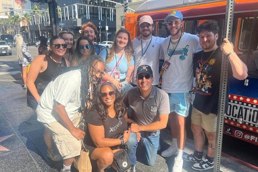 A group of people posing in front of a bus with a sign that reads 'LOCATION'. 3