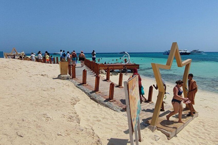 A sandy beach with wooden structures, a wooden deck, and a clear blue sky. 5