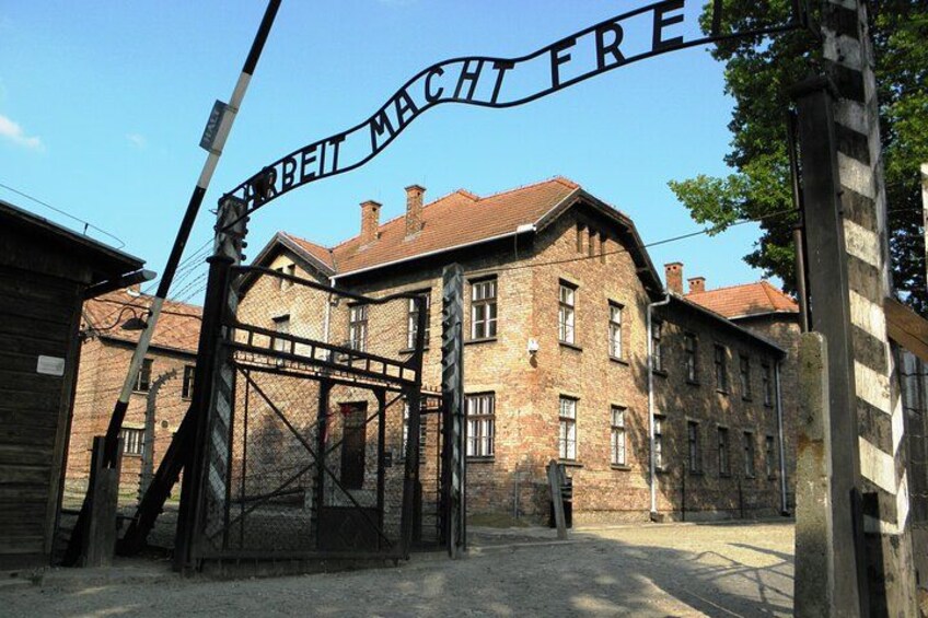 Un edificio histórico con un cartel que dice 'ARBEIT MACHT FREI' y una puerta. 1