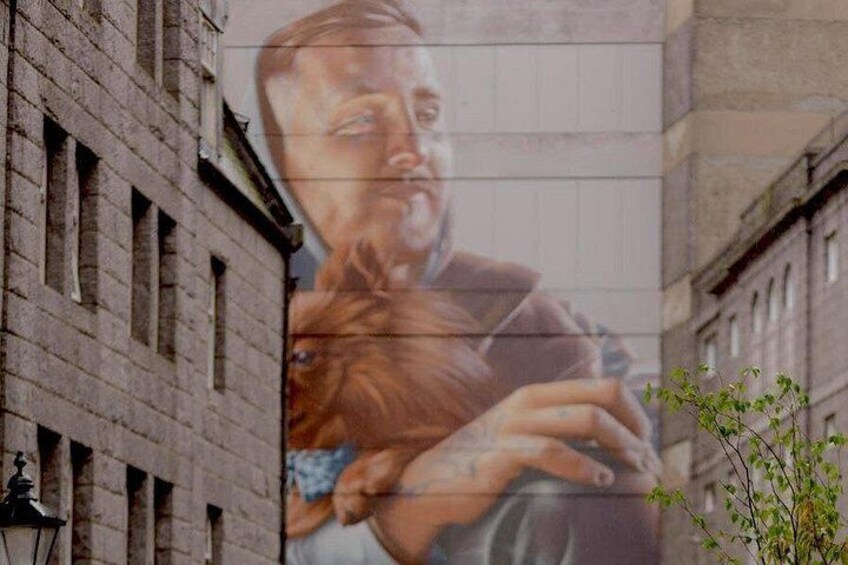 A mural on a building with a person holding a child. 4