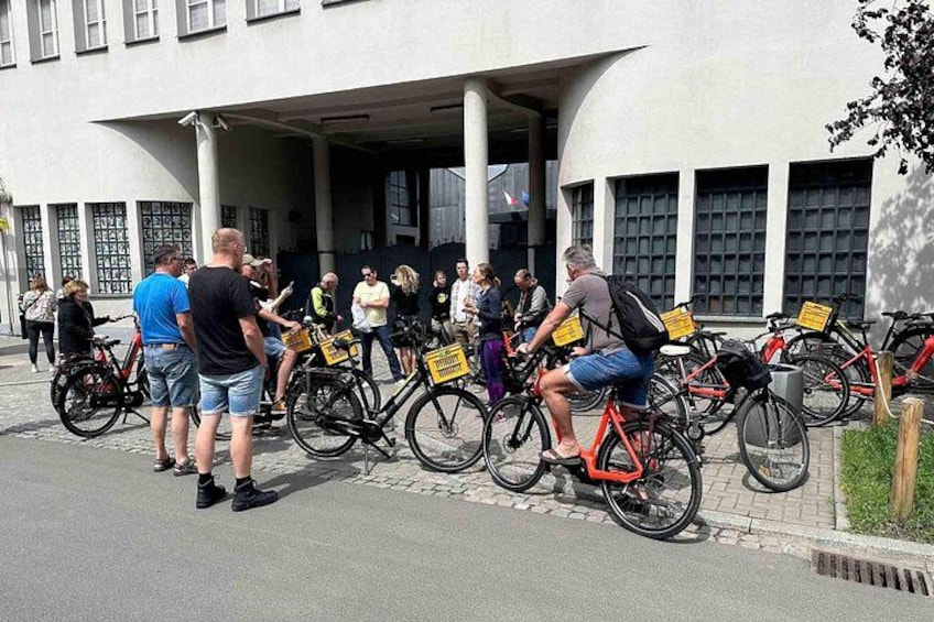 En gruppe mennesker på cykel foran en bygning med søjler. 3