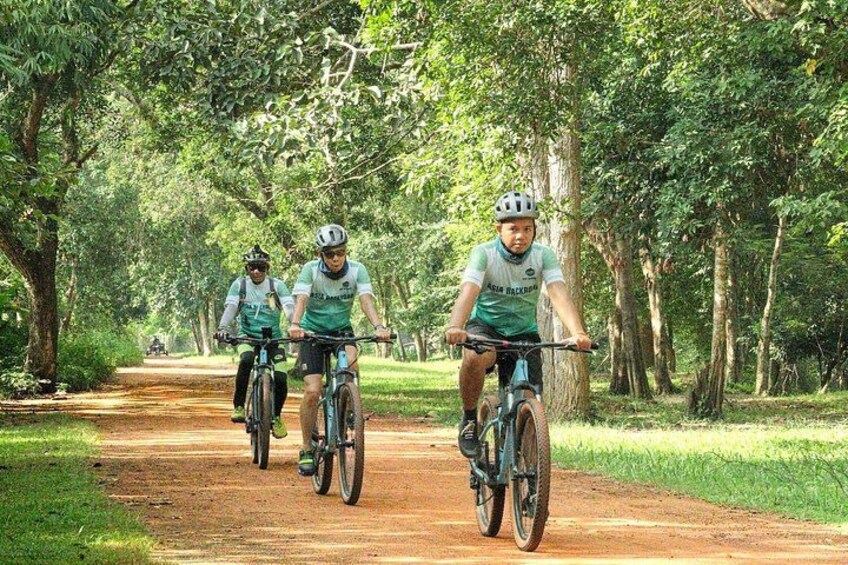 Tres ciclistas en un sendero de tierra rodeado de árboles. 5