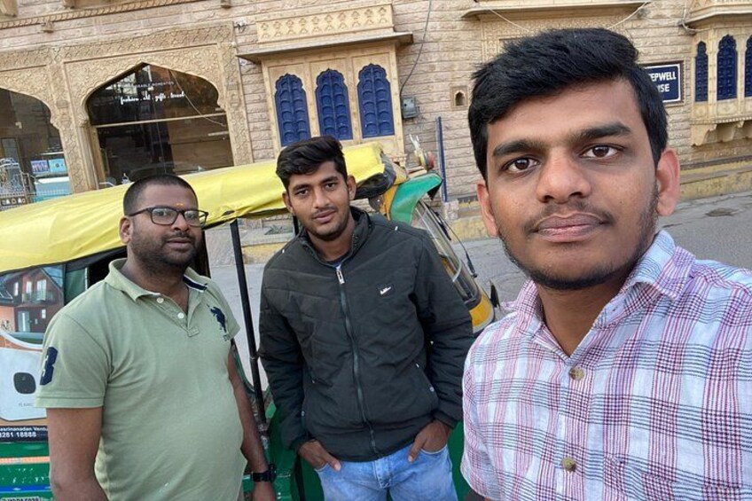 Three men standing in front of a building with blue doors and a yellow canopy. 3