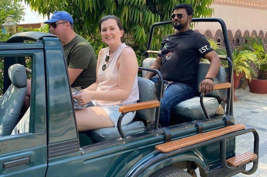A green vehicle with wooden benches, a man in a black shirt, and a woman in a white top. 5