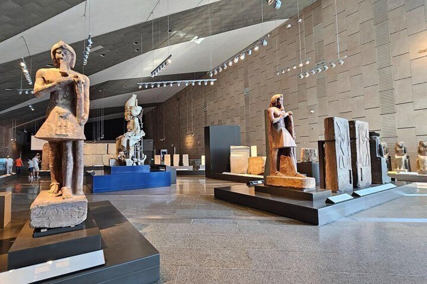 A museum interior with ancient statues and artifacts displayed on pedestals. 3