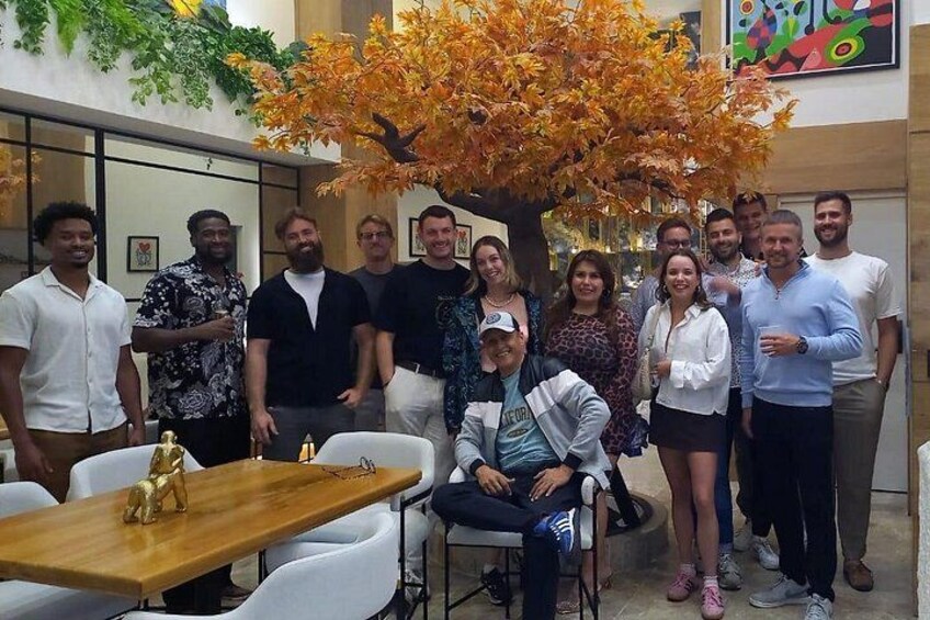 A group of people gathered around a table with a tree in the background. 5