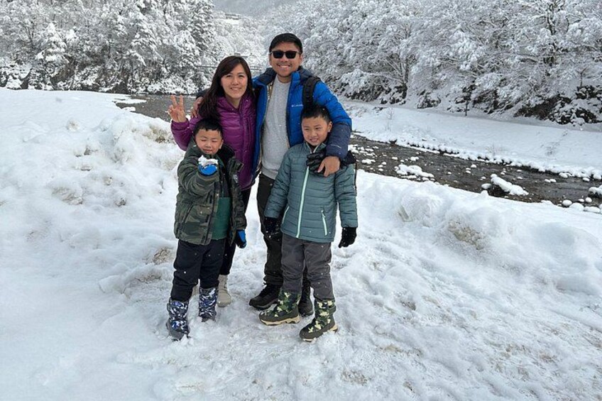 A family of four in a snowy landscape with a river in the background. 2