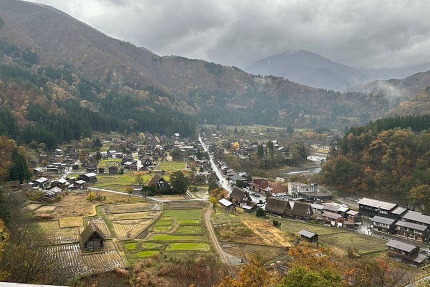 A village nestled in a valley with terraced fields, houses, and a river. 2