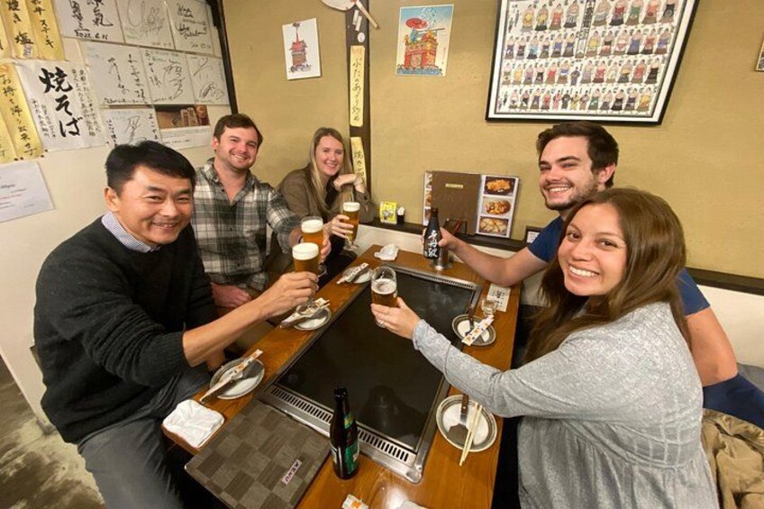 A group of people toasting with beer glasses at a wooden table in a restaurant. 5