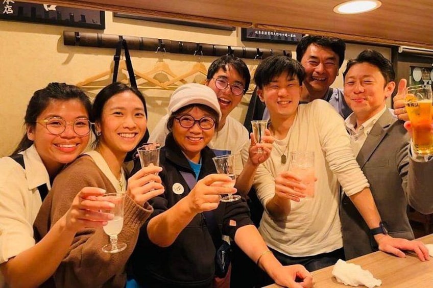 A group of people toasting with drinks at a bar. 1