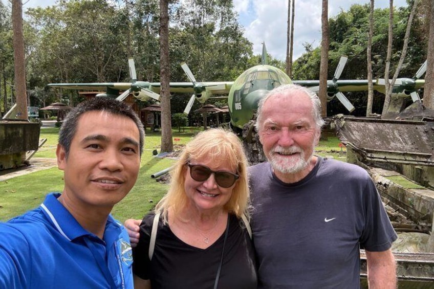 Three people posing in front of a military aircraft display. 1