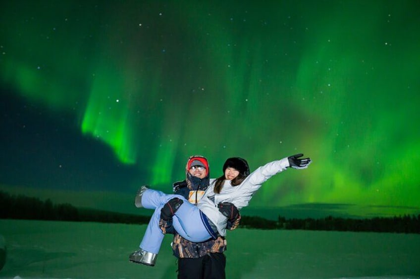 A person being carried by another under a night sky with green aurora. 3