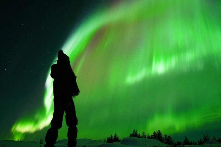 En silhuet af en person foran nordlys. 1