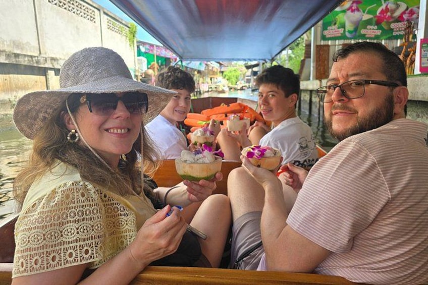 A group of people on a boat, holding drinks with a tropical drink in a coconut shell. 2