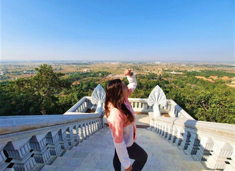 A person standing on a balcony overlooking a landscape with trees and buildings. 1
