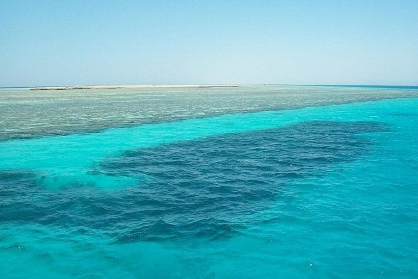 A turquoise sea with a sandy beach and a clear sky. 3