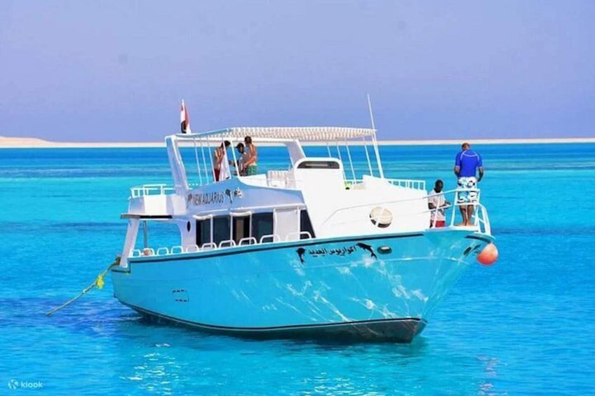A boat with people on it, floating on clear blue water. 4