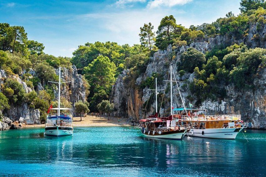A coastal scene with boats docked near a rocky cliff and a beach. 5