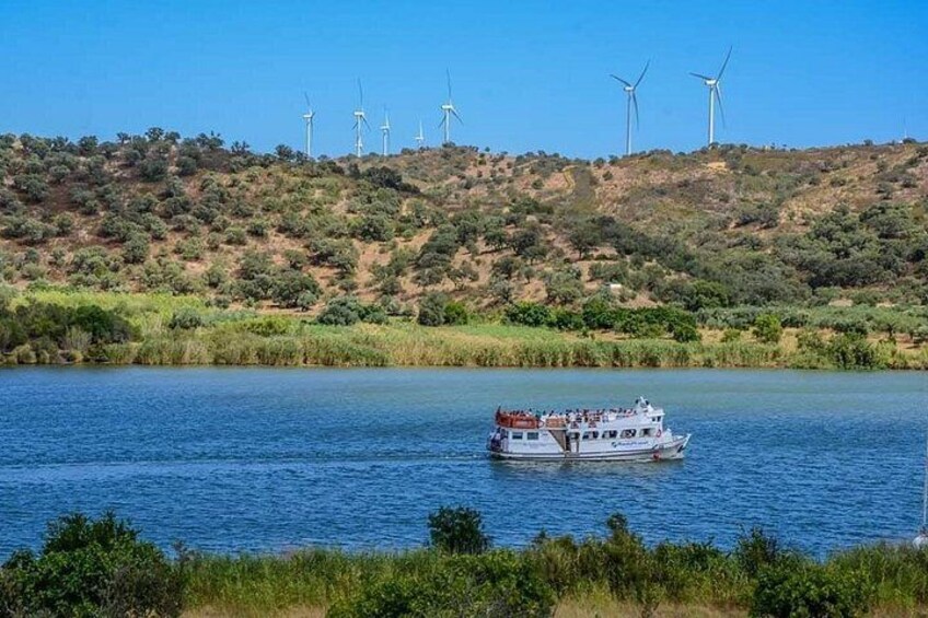 Un bateau sur une rivière, avec des éoliennes en arrière-plan. 1