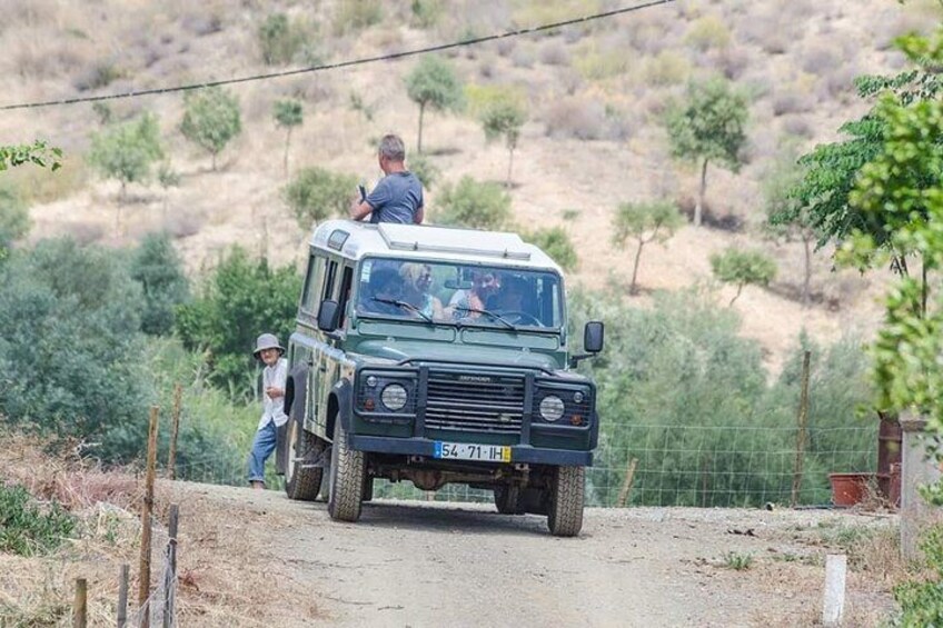 Un vehículo todoterreno verde sobre un camino de tierra, con una persona de pie al lado. 2
