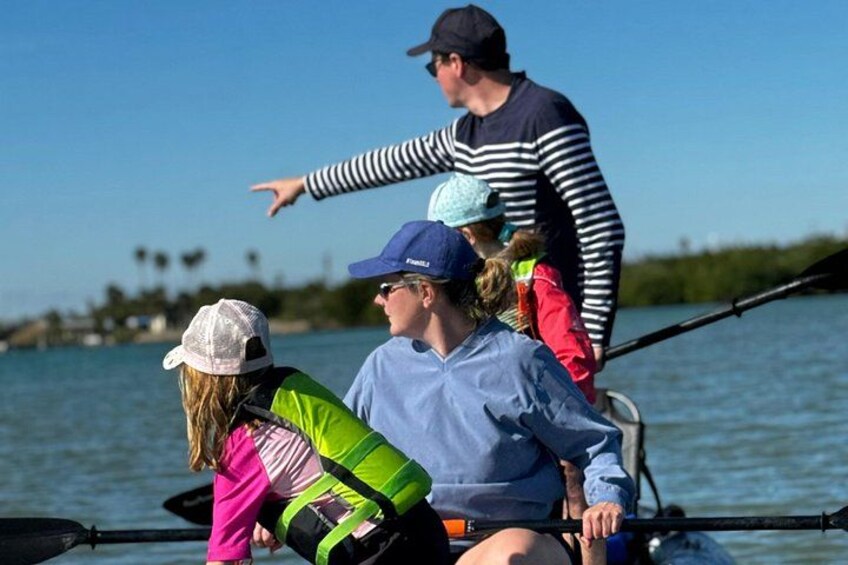 A group of people on a boat with a calm body of water and a clear sky in the background. 1