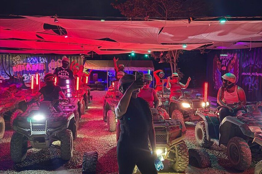 Evento al aire libre con personas en vehículos todo terreno bajo una carpa con iluminación roja. 2