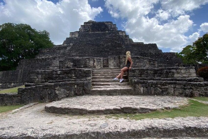 En person sidder på gamle stenhinder, der fører op til en pyramideformet bygning. 2