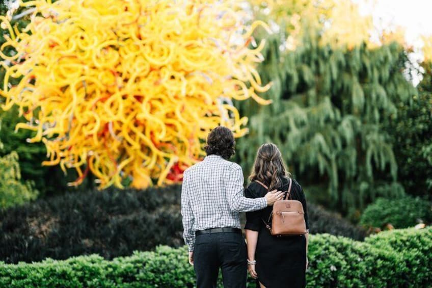 Two people walking in a garden with a large yellow tree. 5