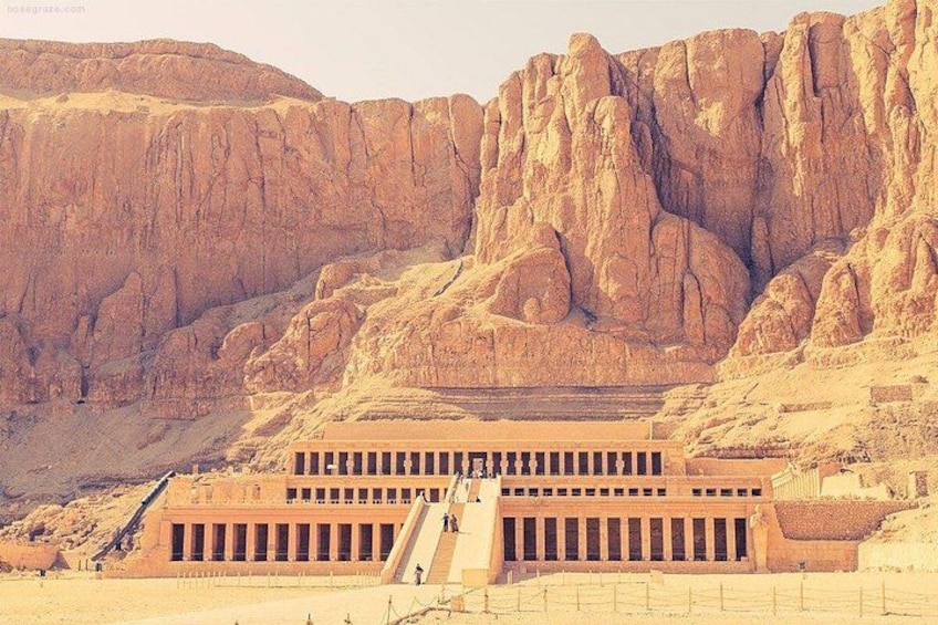 A large, ancient stone structure with a long staircase leading up to it, set against a backdrop of rocky mountains. 4