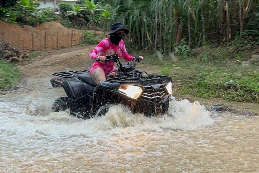 A person on an ATV navigating through a flooded area. 1
