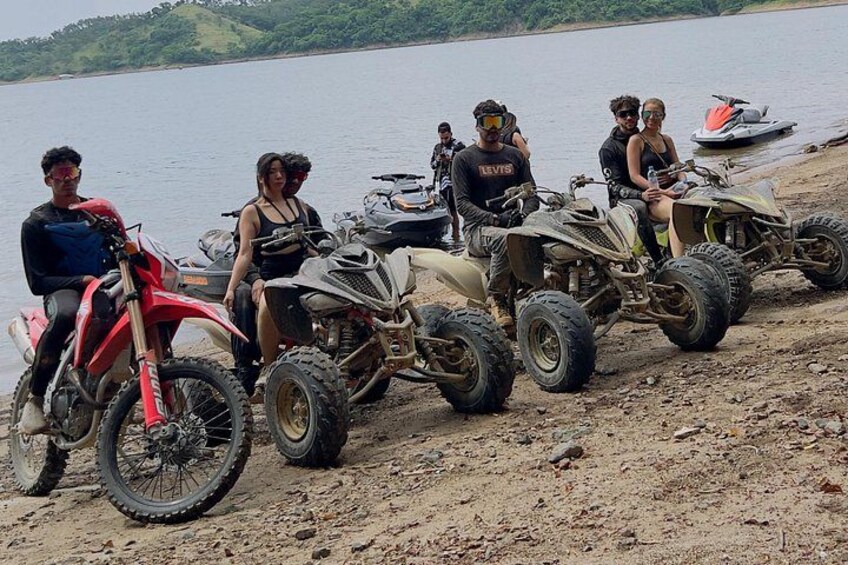 A group of people on ATVs by a lake. 5