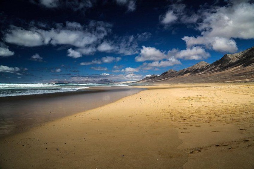 A beach with a clear sky and mountains in the background. 2