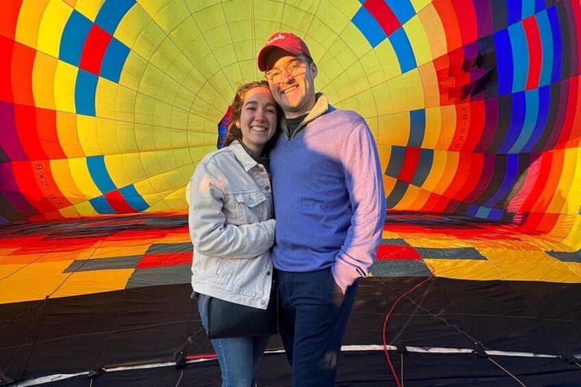 A colorful hot air balloon with a person standing in front of it. 1